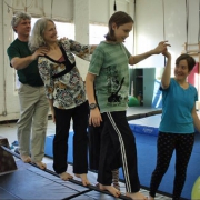 NECCA coach helping a family of three walk across a balancing pipe